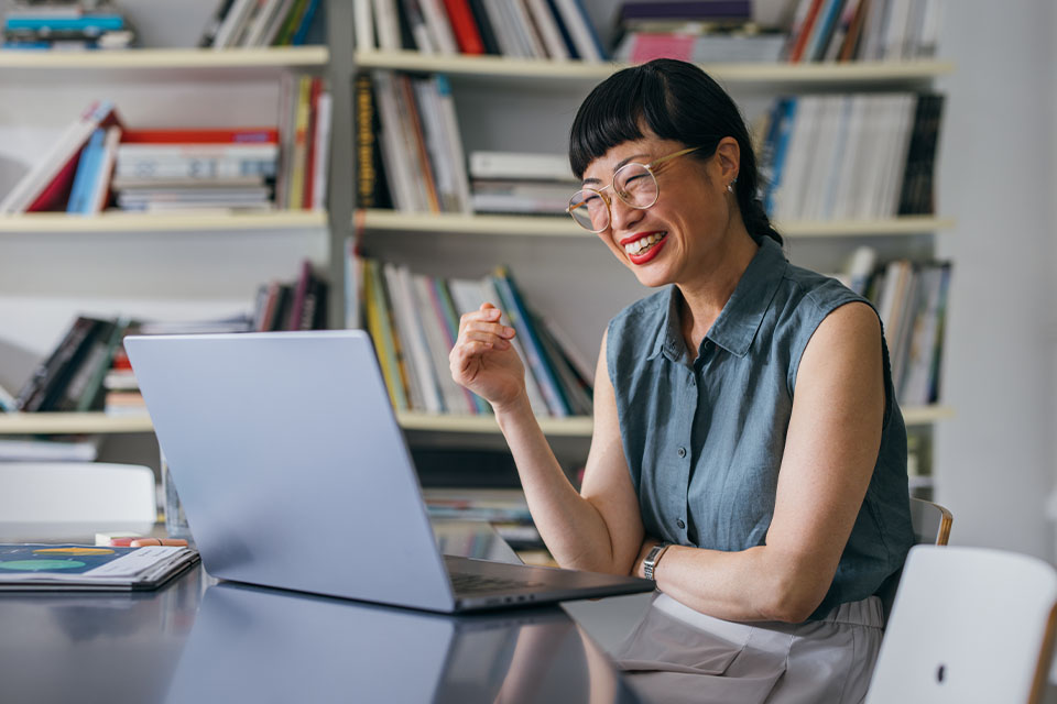 Female student smiles while participating in online business course on her laptop.