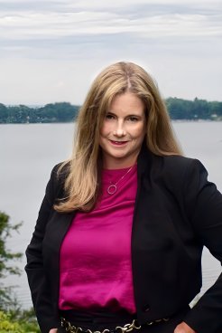 Kristin Haag in purple top and black blazer, looks at the camera.