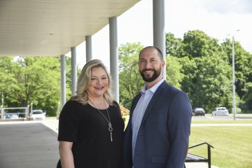 Leslie Corbo and Andrew Carr stand outside Bull Hall, smiling.