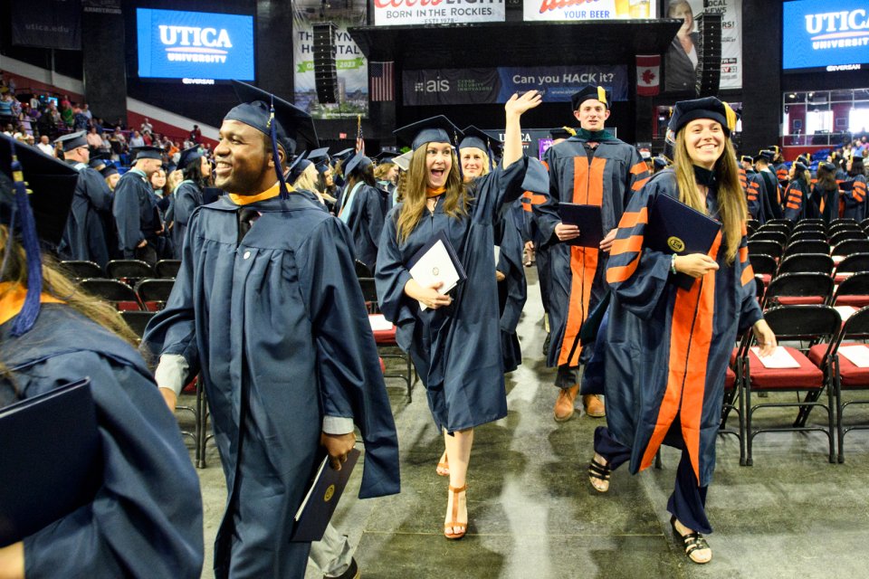 A graduate waves as members of the graduate class of 2022 exits the ceremony with their degrees.