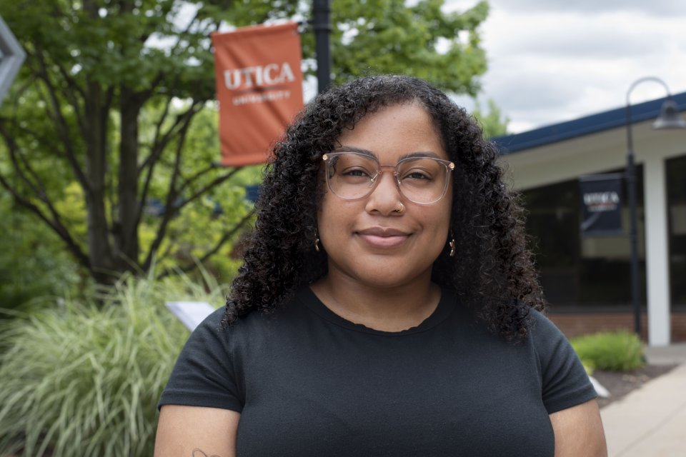 Nevaeh Scott-Dominguez stands in front of a Utica University banner on campus.